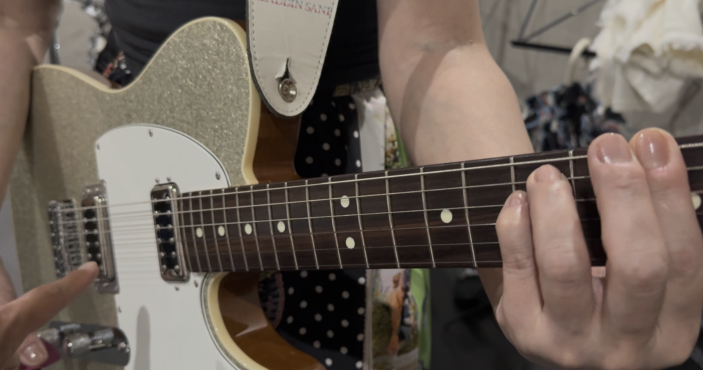 ギター講師がストロークの歯切れを出すための右手の振りをレクチャーしている様子。ブラッシング練習で一瞬のスピード感を出すためのコツを生徒に伝授している指導写真。