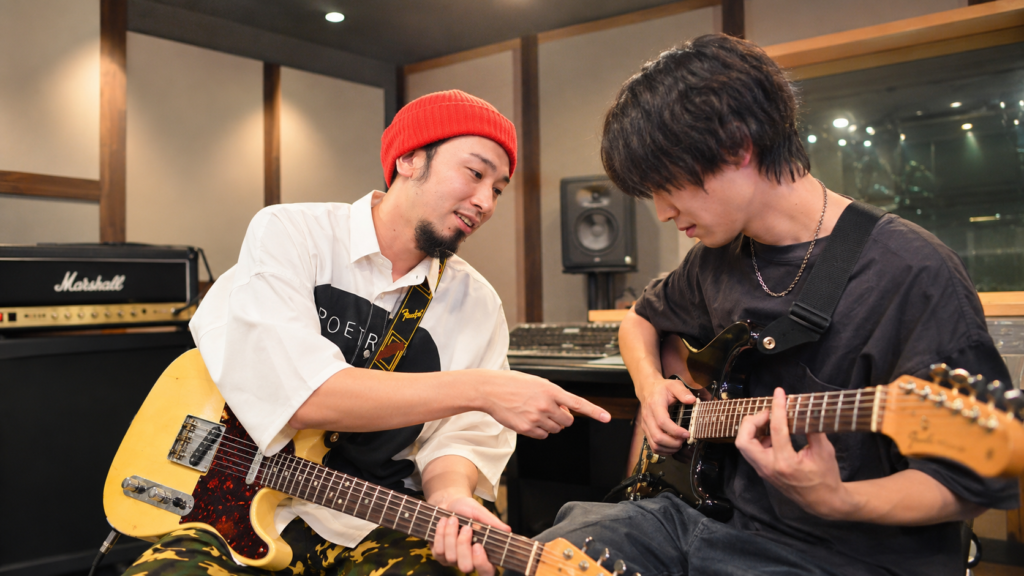 ミューキャンのギター教室の音楽スタジオで、プロ講師からマンツーマンでギター指導を受ける生徒のレッスン風景