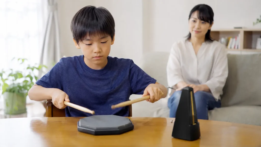 子どもが自宅で練習パッドとメトロノームを使って静かに練習する様子