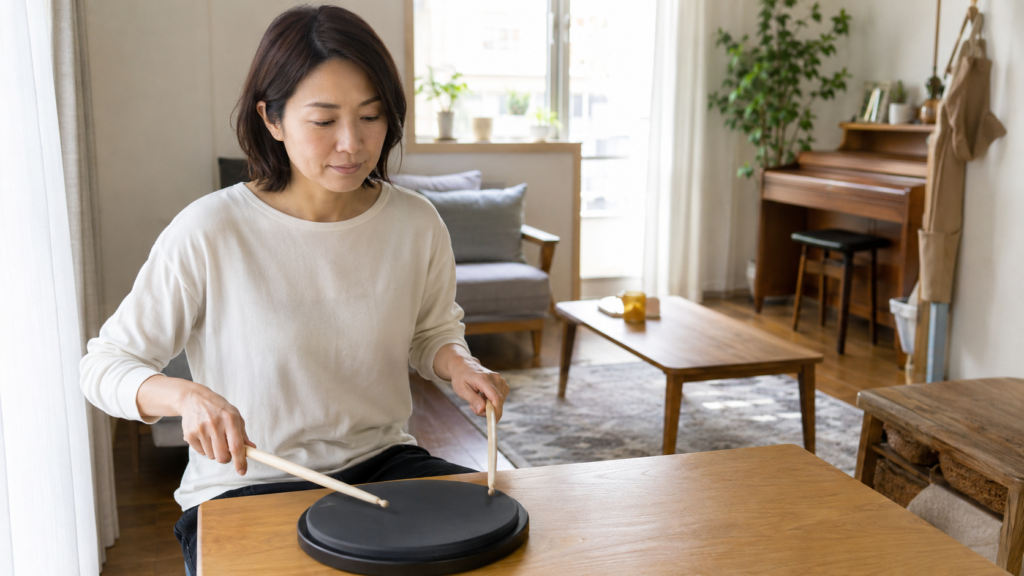 自宅で練習パッドを使いドラムのリズムを確認する大人