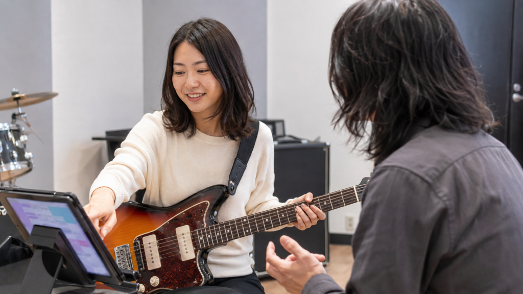 弾きたい曲と練習目標を講師と相談する登戸ギター教室の女性生徒