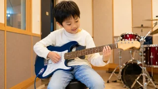 7歳の子どもが体格に合うギターで練習する様子