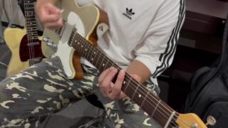 講師がギターを構え、カッティングのストロークと左手のコードフォームを実演する様子