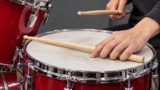 スネアの打面にスティックを沿わせるクローズドリムショットの手元の解説イメージ"